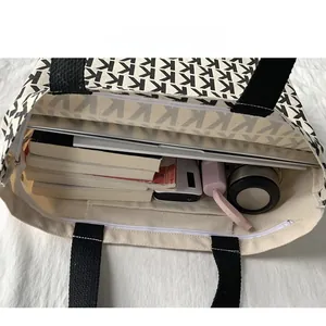 Vista dall'alto di una capiente borsa in tela con laptop, libri e oggetti vari