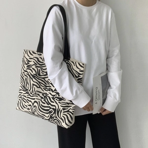 Détail d'un grand sac cabas en toile zébrée montrant la texture des rayures noires et blanches