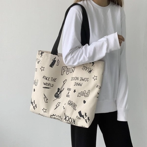 Vue détaillée d'un grand sac cabas en toile avec motifs graffiti rock et bandoulières noires