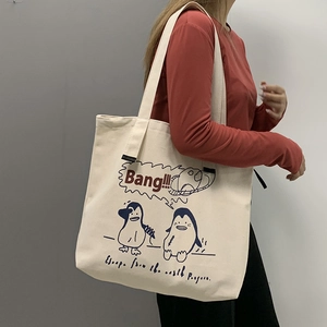 Detail of off-white canvas tote bag featuring cute penguin prints and typography