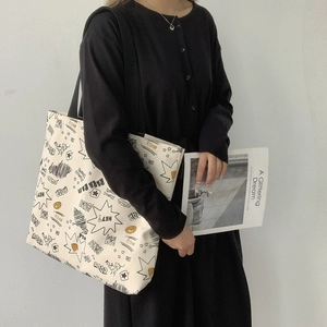 White canvas tote bag set with American comic graffiti worn by a model in black dress