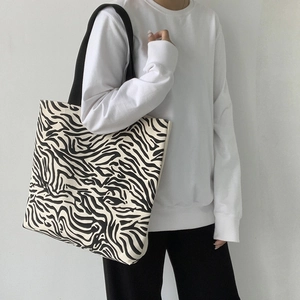 Détail d'un grand sac cabas en toile à imprimé zèbre avec de larges bretelles noires