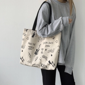 Détail du sac fourre-tout en toile beige avec motifs rock et large bandoulière
