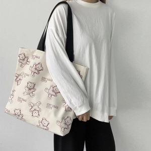 Detail of canvas shoulder bag with cute purple bear prints and black straps on model