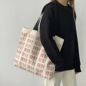 Detail of white canvas tote bag featuring red Chinese character pattern and wide strap