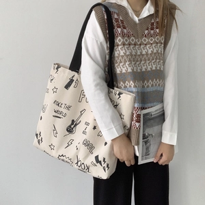 Détail du sac cabas en toile blanc cassé avec graffitis rock noirs et large bandoulière
