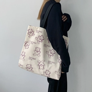 Detail of off-white canvas tote bag featuring purple bear print and black strap