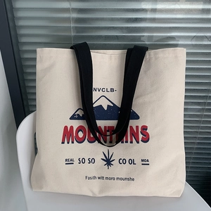 Close-up of canvas tote bag featuring blue mountain print and black handles