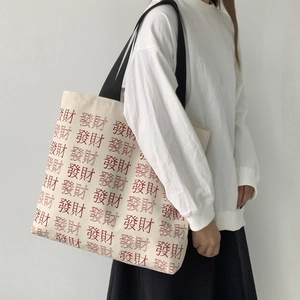 Detail of canvas tote bag with red Chinese character print and wide black strap