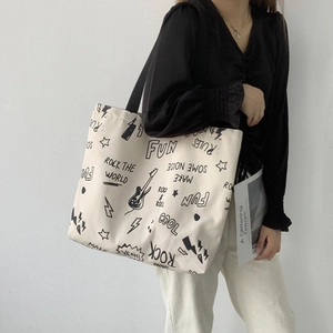 Détail du sac cabas en toile crème avec imprimés graffiti rock et bandoulière large
