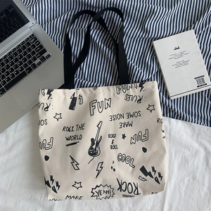 Détail d'un grand sac cabas en toile avec des graffitis rock noirs sur fond bleu