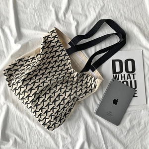Dettaglio borsa tote in tela color avena con stampa ripetuta di lettere K nere