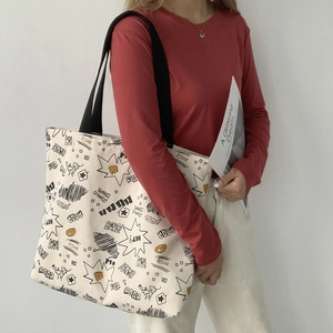 Detailed view of canvas tote bag with comic graffiti patterns and wide black shoulder strap