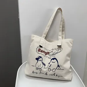Detail of penguin cartoon print and red Bang text on beige canvas tote bag surface