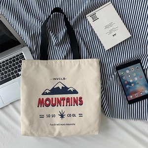 Detailed shot of beige canvas tote bag with mountain print on blue striped fabric
