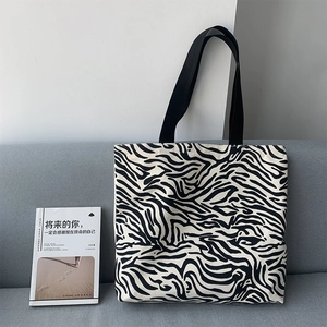 Détail d'un sac cabas en toile à motif zèbre avec larges bandoulières et grande capacité
