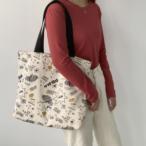 Off-white canvas tote bag with comic cartoon print and black shoulder straps