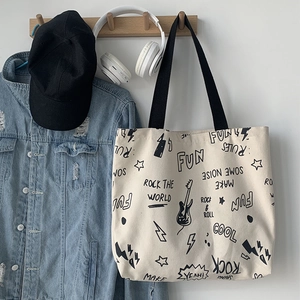 Détail du sac fourre-tout en toile beige avec graffitis rock et anses noires