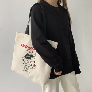 Detail of white canvas tote bag with red Getup text and cute cartoon bear illustration