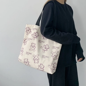 Detail of canvas tote bag with purple bear pattern and black straps on model shoulder