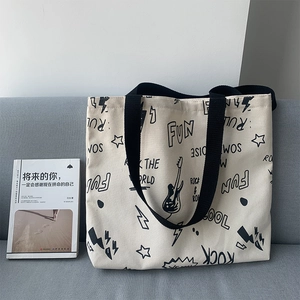 Détail d'un cabas en toile beige avec graffitis rock sur un canapé gris