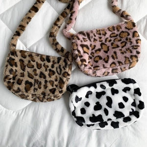Three plush leopard and cow print crossbody bags with zippers on white quilted fabric