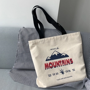 Detailed macro view of the mountain graphic and font on a beige canvas tote bag