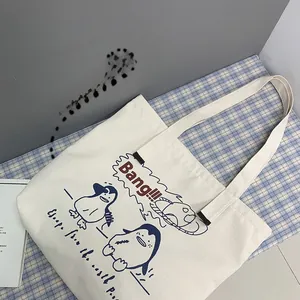 Detail of a beige canvas tote bag with a cartoon penguin print and Bang lettering