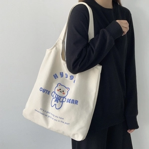 Dettaglio della borsa tote in tela bianca con stampa di orso blu e scritta Hygge