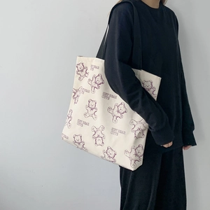 Detail shot of white canvas tote bag with purple bear print and black shoulder straps