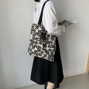 Détail du sac fourre-tout en toile beige avec motifs de feuilles et texte A Lucky Day