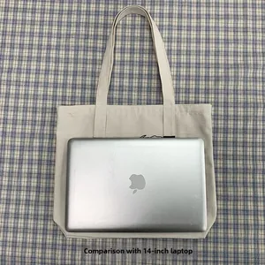 Detailed comparison of the large beige canvas tote bag with a 14-inch laptop device