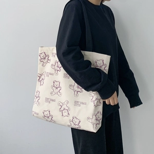 Detail of off-white canvas tote bag featuring cute purple bear print and side shoulder view