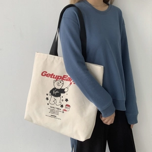 Detail of canvas tote bag with GetupEar red text and bear illustration on off-white fabric