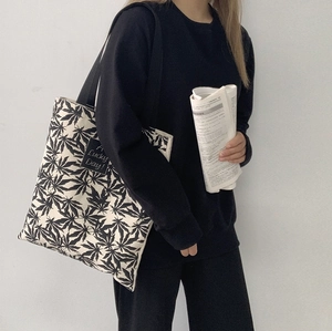 Détail du sac fourre-tout en toile à motif feuilles noires et étiquette Lucky Day
