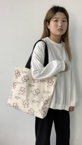 Detail of canvas tote bag featuring purple cartoon bear print and wide shoulder strap