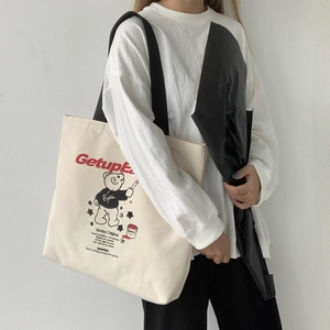 Detail of canvas tote bag featuring bear graphic and GetupEarly text with black strap