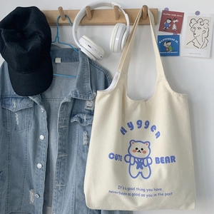 Dettaglio della borsa tote in tela crema con stampa di orso blu e spalline lunghe
