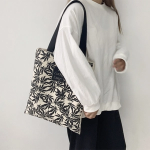 Détail du sac cabas en toile avec motif de feuilles noires et écusson Lucky Day
