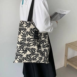 Gros plan d'un sac cabas en toile avec imprimés de feuilles noires et étiquette tissée