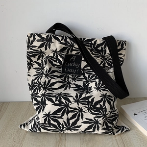 Détail d'un sac cabas en toile crème avec motifs de feuilles et étiquette A Lucky Day