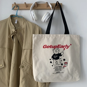 Detail of a large beige canvas tote bag with bear graphic and Vamtac Original branding