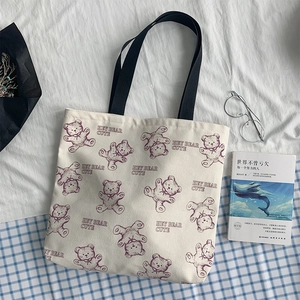Detail of canvas tote bag featuring purple bear prints and black webbing handles
