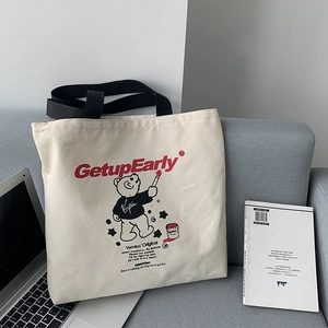 Detail of canvas tote bag with bear graffiti and Getup Early text on a sofa