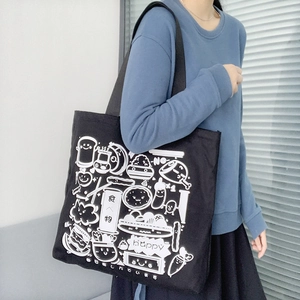 Detail of black canvas tote bag featuring white food illustration and spacious shoulder strap