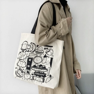 Detailed view of canvas tote bag with black doodle food prints and woven shoulder strap