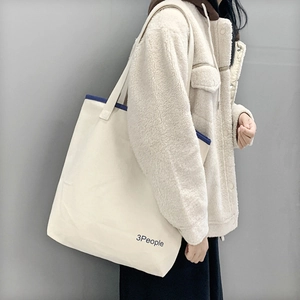 Dettaglio di una grande borsa tote in tela crema con bordo blu e scritta 3People