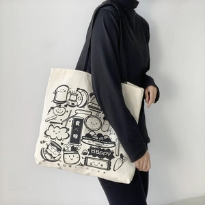 Detail of white canvas tote bag featuring minimalist black food illustrations on shoulder