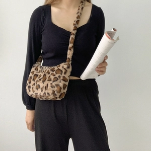 Crossbody leopard print plush bag worn by model over a minimal white background