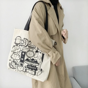 Detail of white canvas tote bag with black cartoon food prints and wide shoulder strap